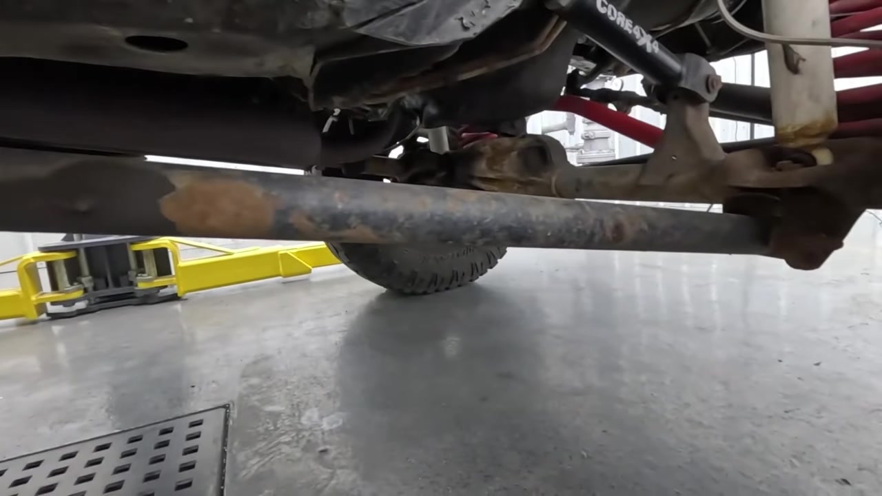XJ Cherokee on lift showing old unmarked long arm kit with worn polyurethane bushings