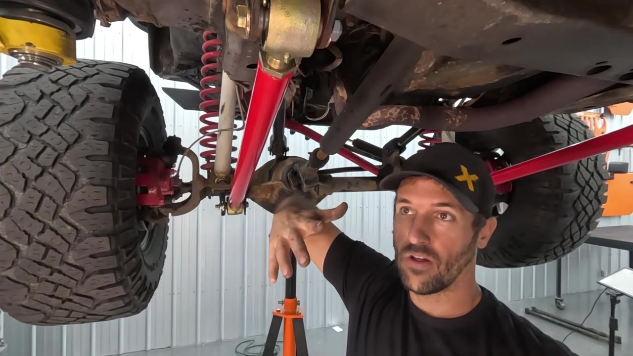 Spence demonstrating jam nut torquing under XJ with new red Core 4x4 long arms installed