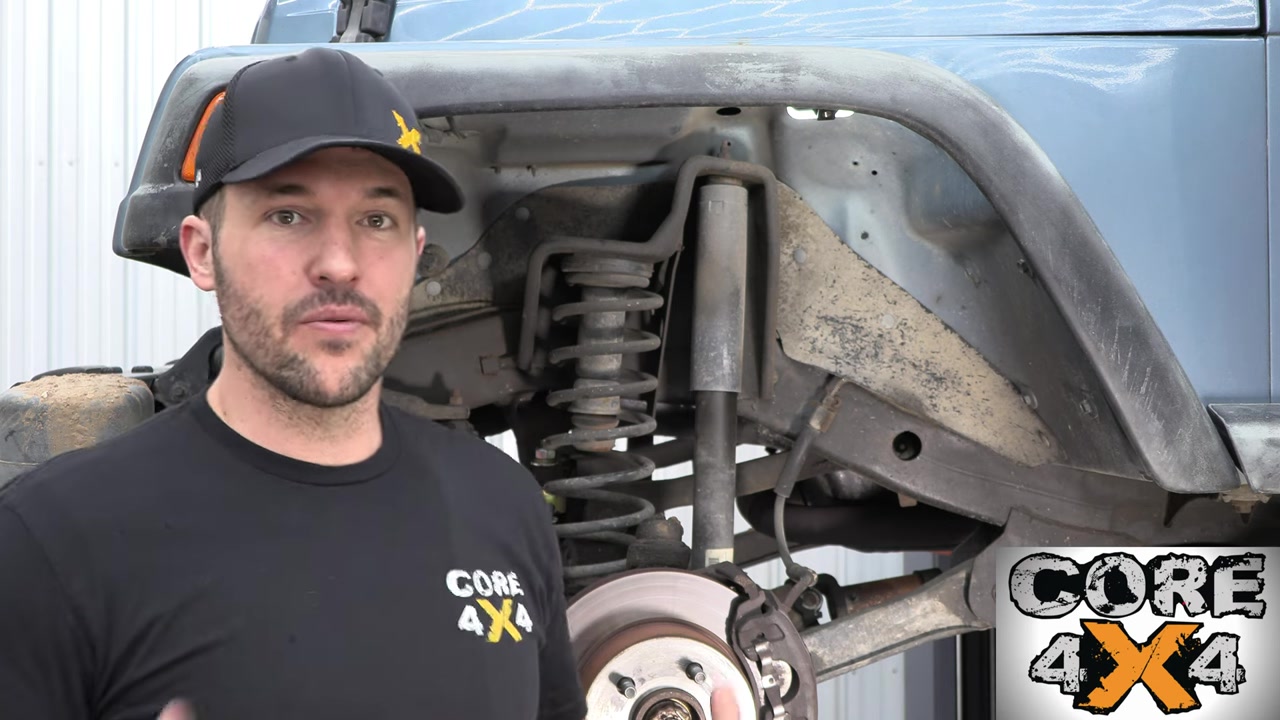 Front suspension teardown on the TJ Wrangler showing factory coil spring and shock