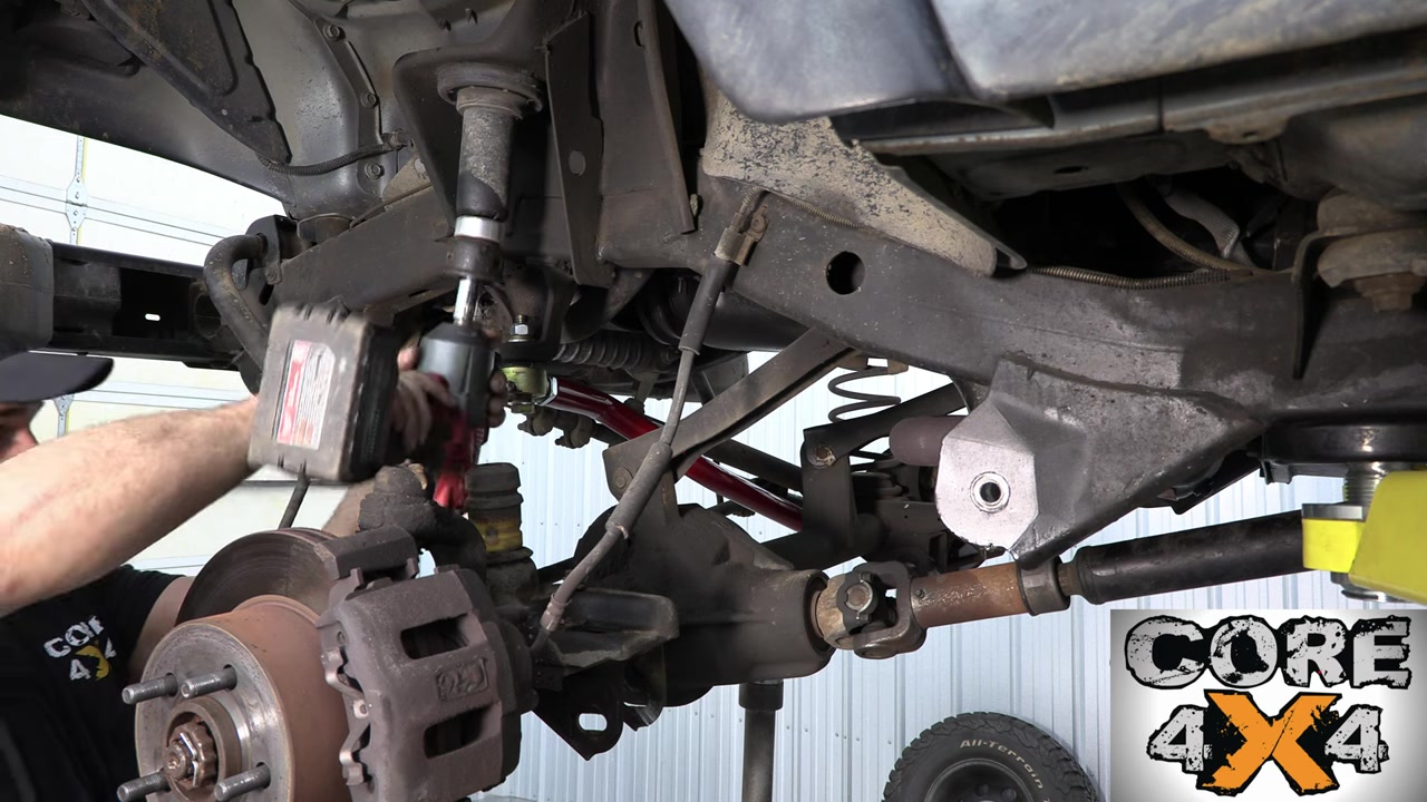 Installing new Core 4x4 lower control arm on the TJ front axle with new coil spring visible