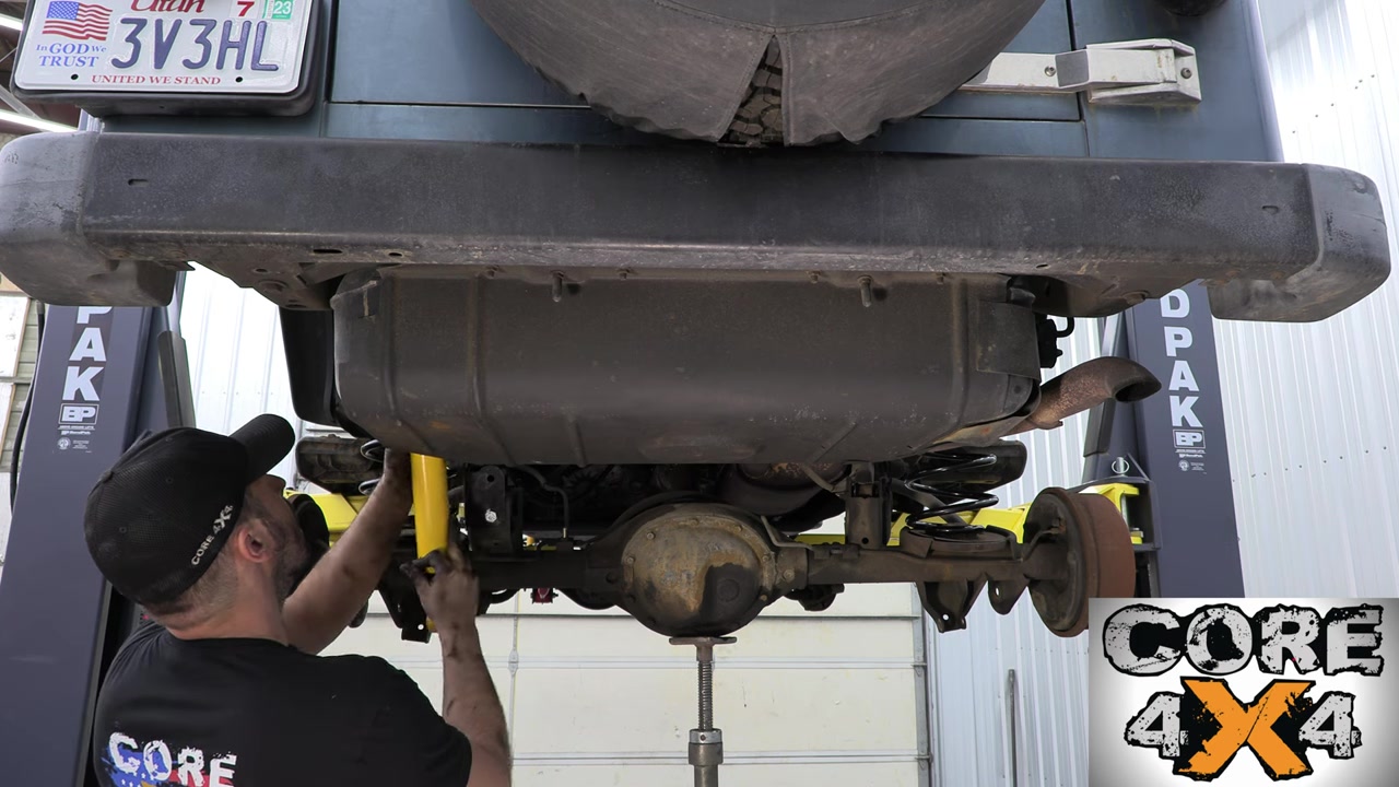 Spence installing rear components under the TJ with new yellow shocks and control arms visible