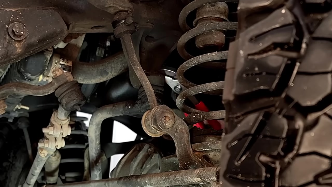 Close-up of the factory TJ track bar and worn suspension components during removal