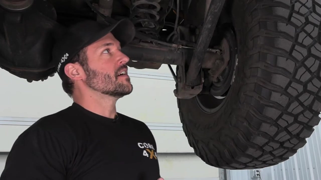 Core 4x4 technician inspecting control arm Johnny Joints underneath a Jeep JK