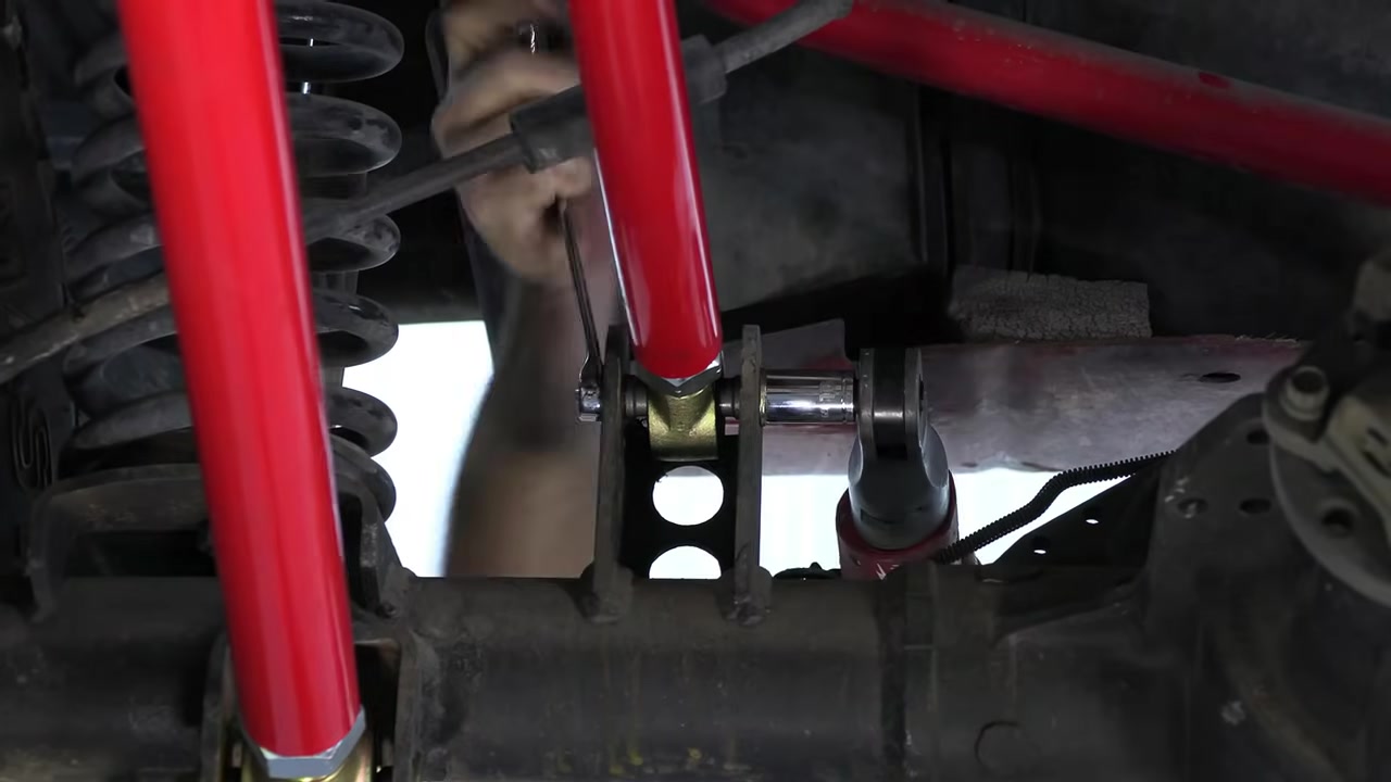 Close-up of the front frame bracket and control arms installed under the ZJ showing the bolt pattern and clearance