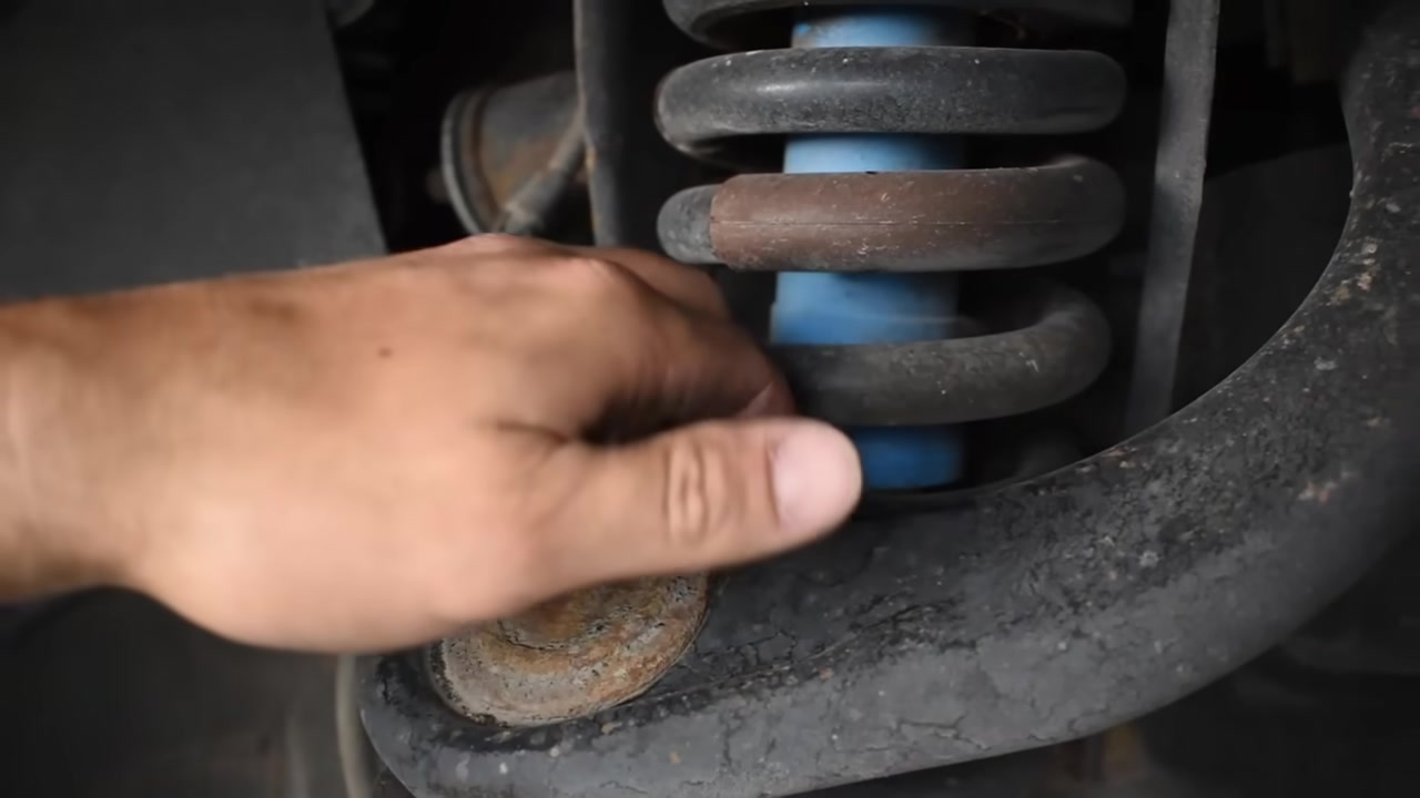 Close-up showing factory upper control arm contacting the coilover at full droop on a lifted Toyota Tacoma