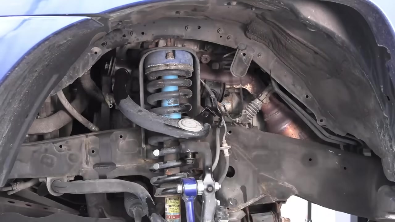 Completed CORE 4X4 upper control arm installation on Toyota Tacoma driver side showing full wheel well with new blue UCA and coilover