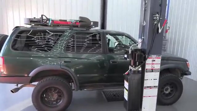 Green third-gen Toyota 4Runner parked in the Core 4x4 shop next to the lift before the rear control arm install