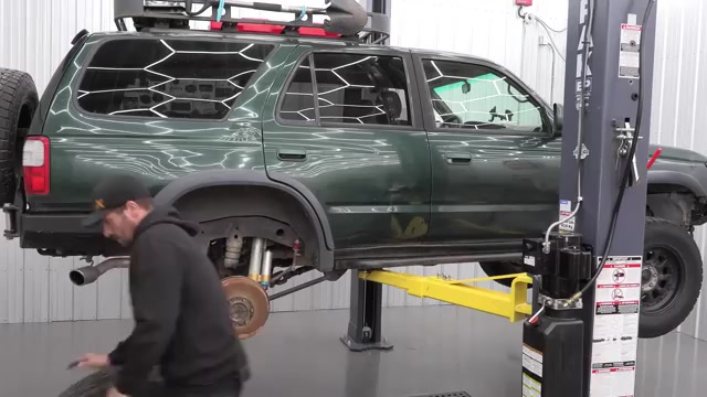 Third-gen 4Runner raised on the two-post lift with rear wheels removed and suspension exposed for the control arm swap