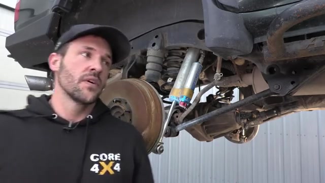 Spence underneath the 4Runner pointing out the rear suspension components including the shock reservoir and factory control arm