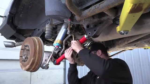 Spence installing a new red Core 4x4 Camp Series rear control arm on the third-gen 4Runner with the axle visible above
