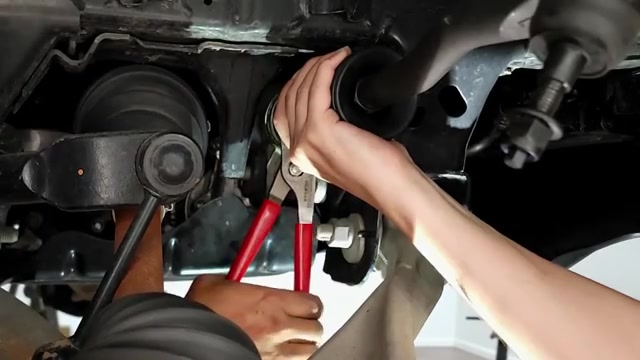 Working on passenger-side suspension with channel locks during the Bronco lift kit install