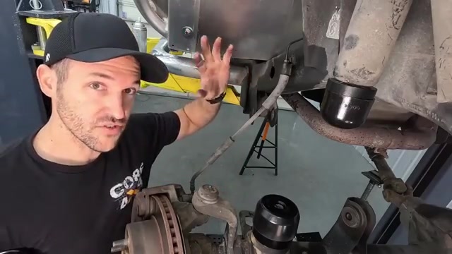 Spence pointing at the front axle area showing the coil spring pocket and brake components on the LJ