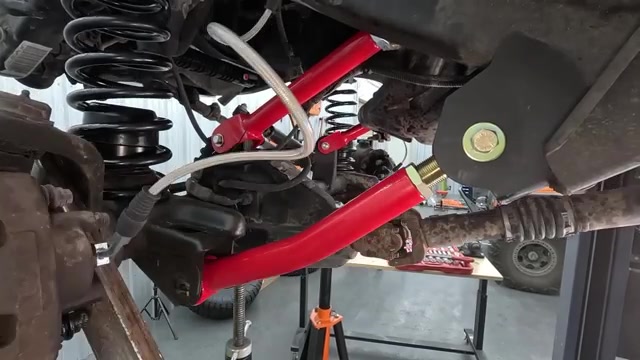 Front suspension of the LJ showing red Core 4x4 control arms installed with new coil springs and brake lines