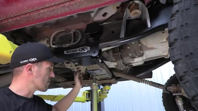 Spence positioning the Core 4x4 long arm bracket under the Ram 3500 frame rail with a jack stand