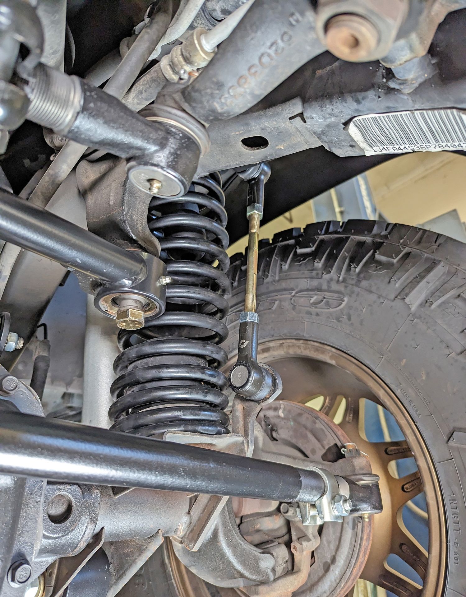 Currectlync drag link installed on the Jeep LJ showing the connection at the pitman arm and the heavy-duty tie rod running to the knuckles