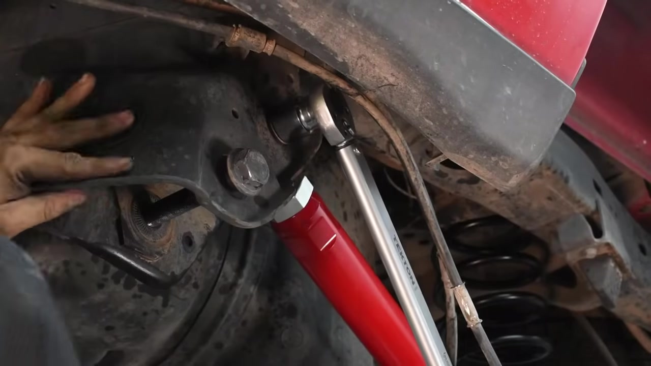 New red Core 4x4 aluminum upper control arm being bolted to the Ram 2500 rear axle bracket