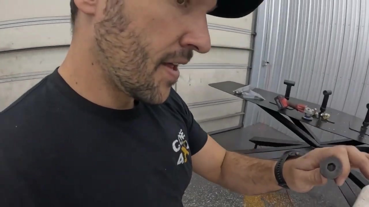 Close-up of Spence examining a sanding pad next to the aluminum table base with flat-top mounting hardware visible