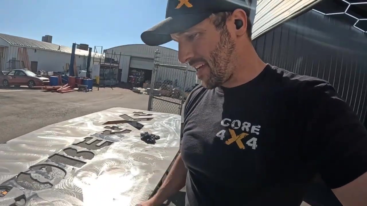 Spence smiling while checking the progress of sanding on the aluminum tabletop outside the Core 4x4 facility