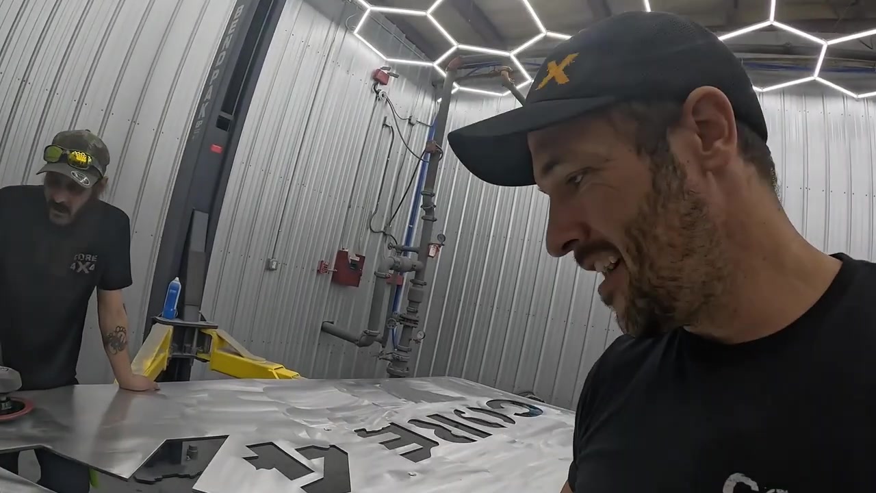Tyson and Spence in the Core 4x4 shop polishing the aluminum tabletop with the Core 4x4 logo visible under the buffed surface