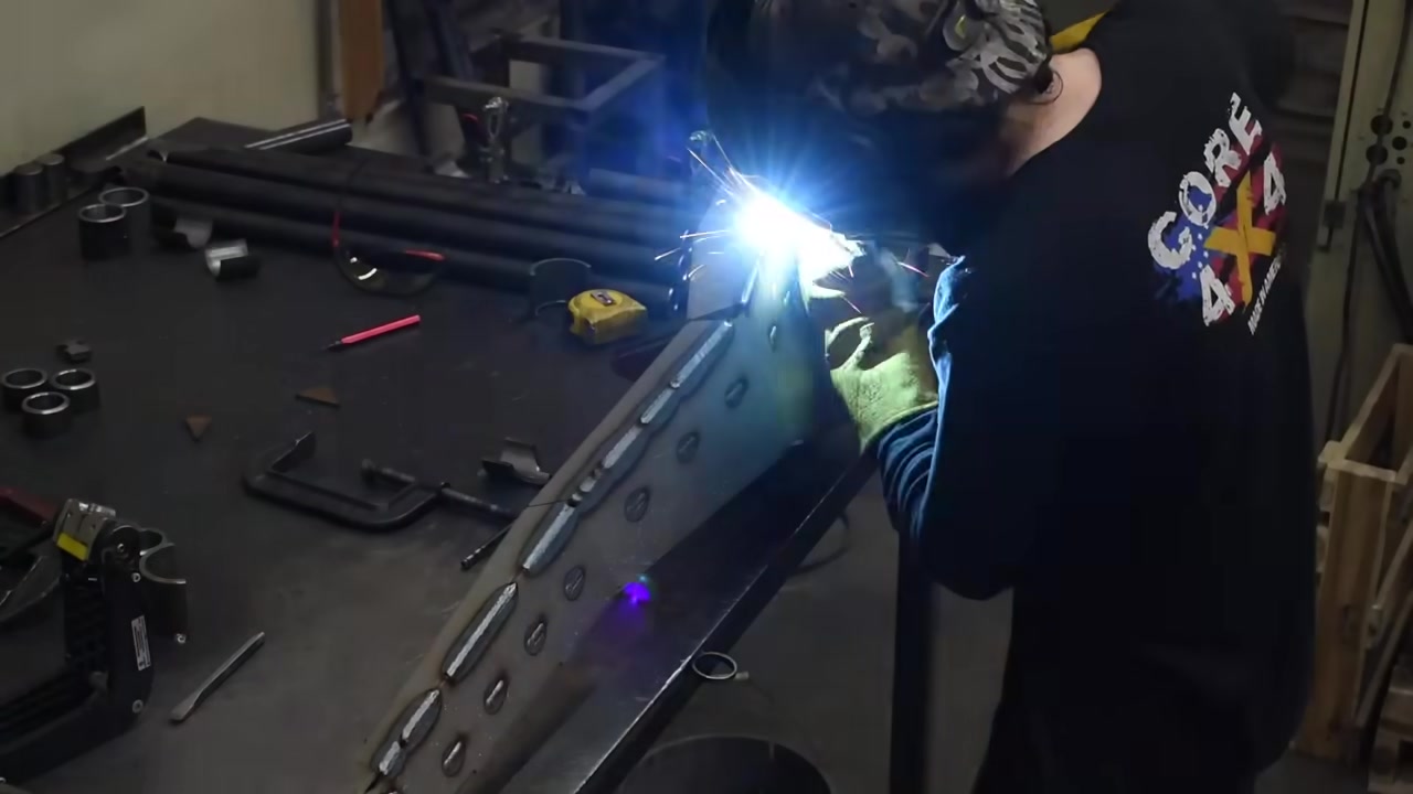 Core 4x4 technician welding a radius arm in the fabrication shop