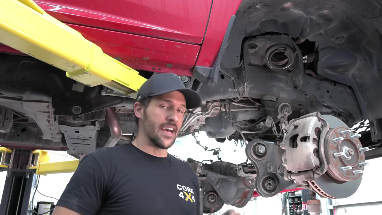 Factory front suspension fully removed from the Ram 2500 with the axle drooped and supported on jack stands