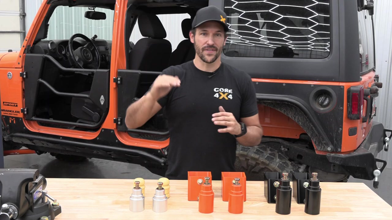 Spence explaining bump stop sizes on a workbench with the Core 4x4 2-inch, 3-inch, and 4-inch bump stop extensions and factory bump stops laid out