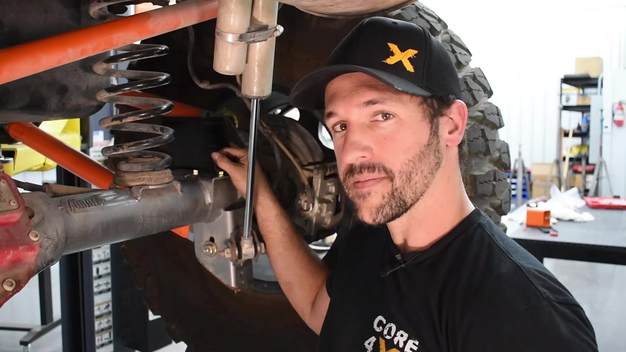 Spence installing the front bump stop extension on the Jeep JK, reaching up into the coil bucket area near the frame
