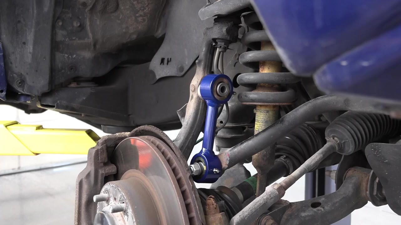 New Core 4x4 heavy duty anodized blue sway bar end link installed on the Tacoma front suspension, connecting the sway bar to the spindle