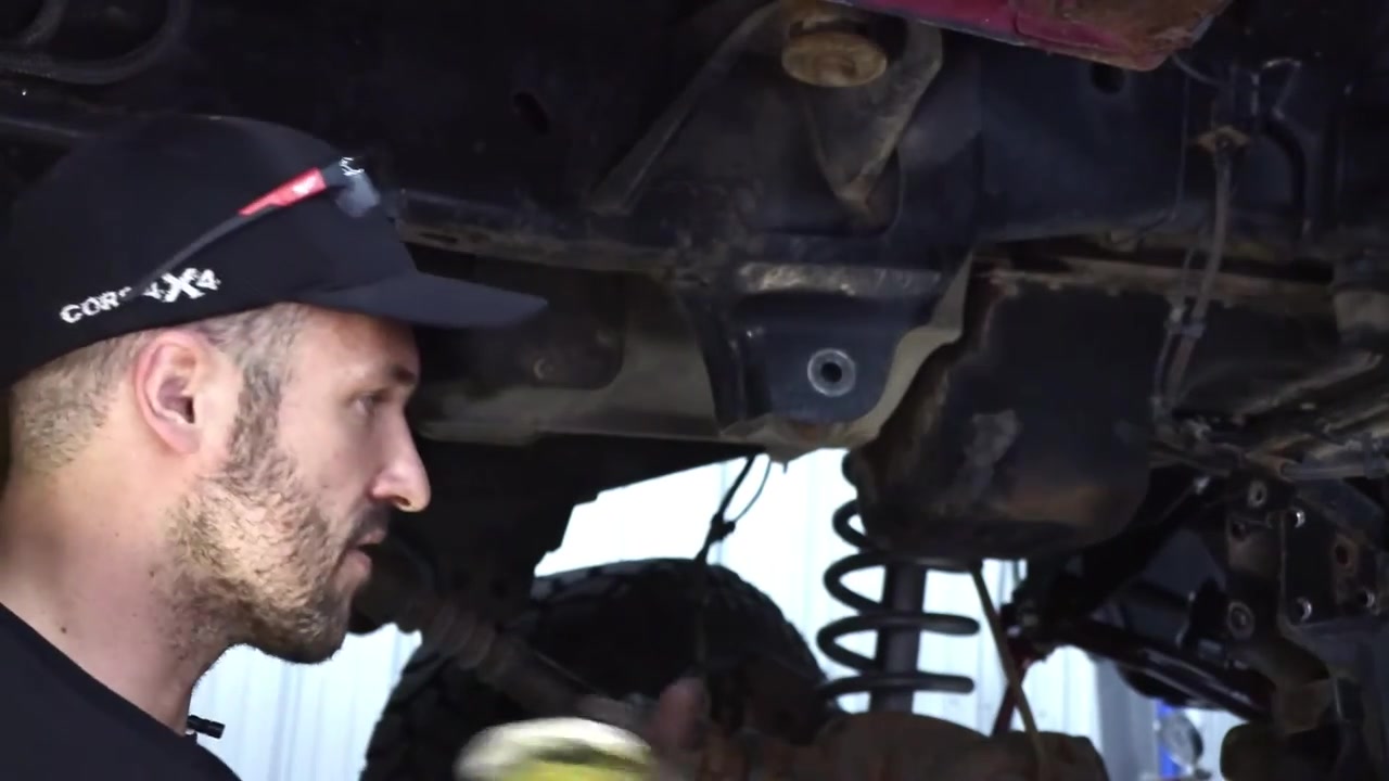 Spence examining the factory lower control arm mounting bracket on the Ram 3500 frame before cutting it off
