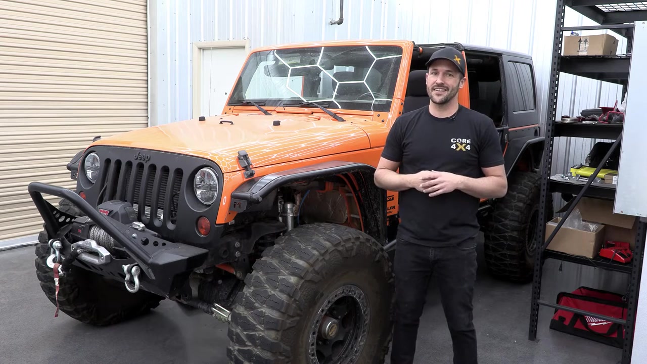 Orange Jeep JK Wrangler on 40-inch tires in the Core 4x4 studio ready for long arm tear down