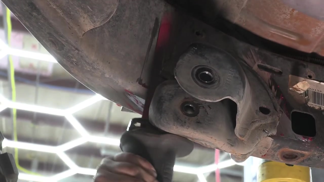 Close-up of JK Wrangler front factory control arm bracket being cut from the frame