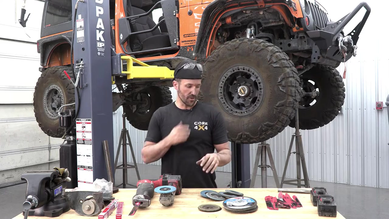 JK Wrangler on lift with all factory brackets removed and frame cleaned up, tools laid out on workbench in foreground