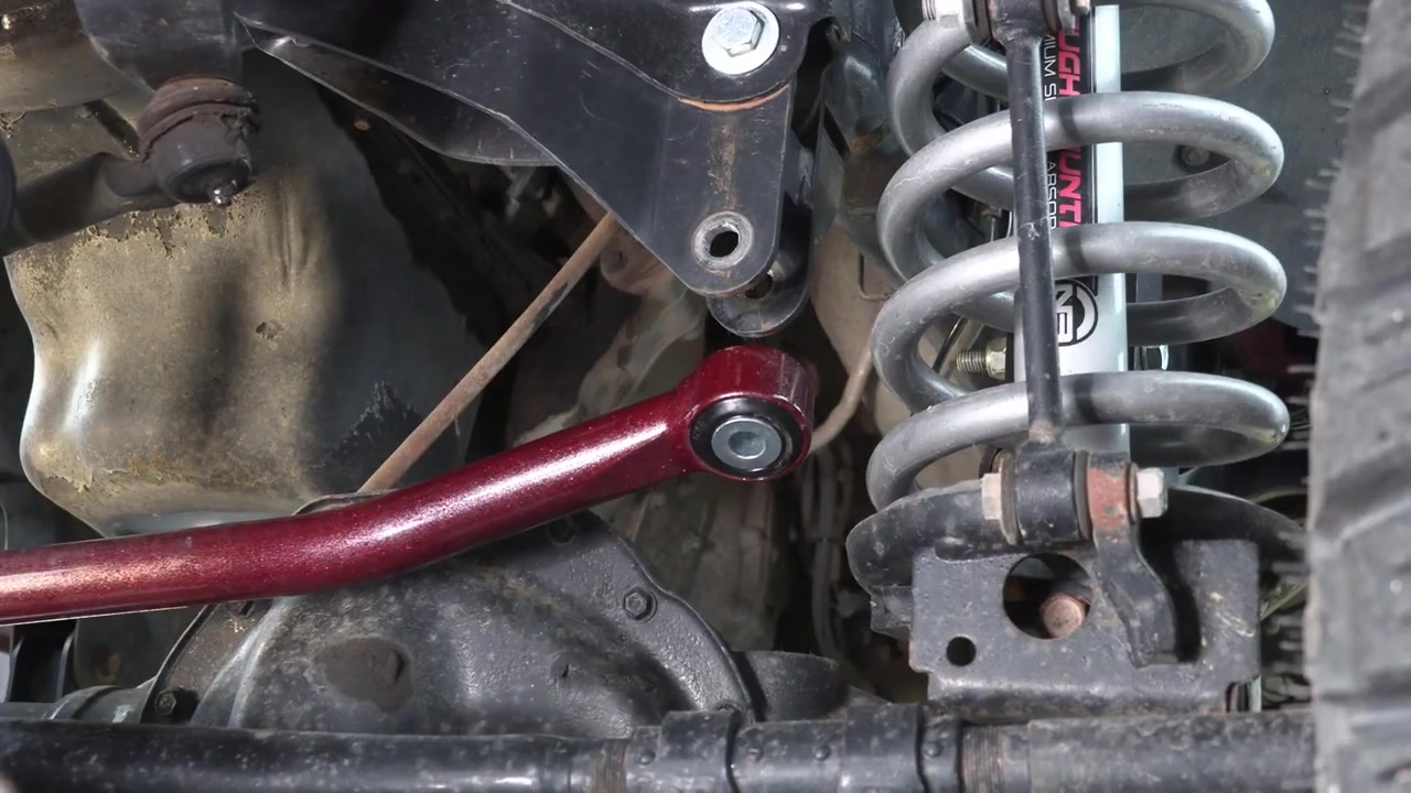 New Core 4x4 track bar installed on the front axle of the Ram 3500 showing the cherry powder coat finish