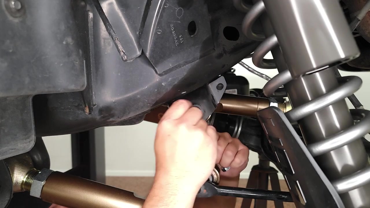 Spence installing the new Core 4x4 Crawl Series rear sway bar end link on the Bronco, guiding the Johnny Joint into the frame-side mounting point