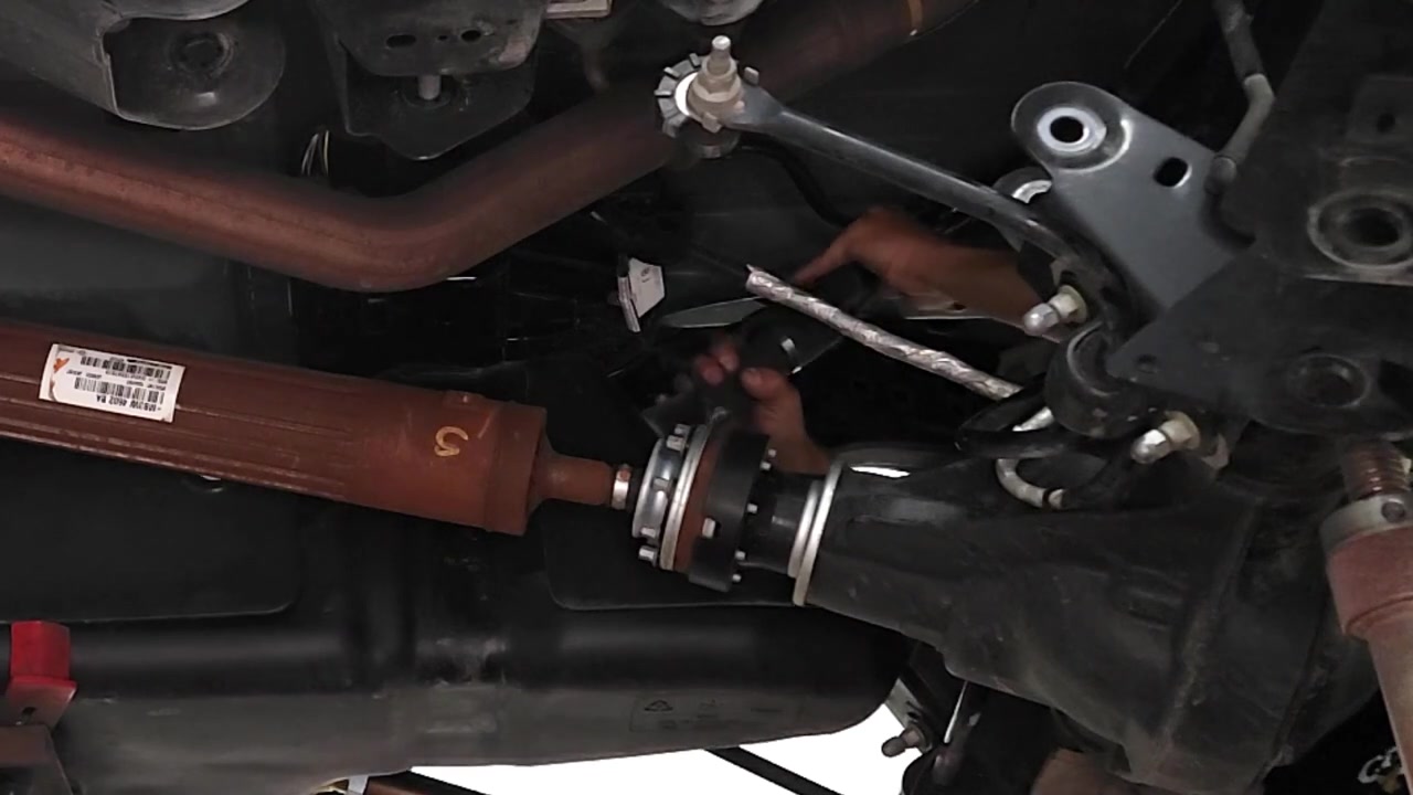 Torquing the rear control arm bolt on the driver side of the Ford Bronco with a torque wrench under the truck