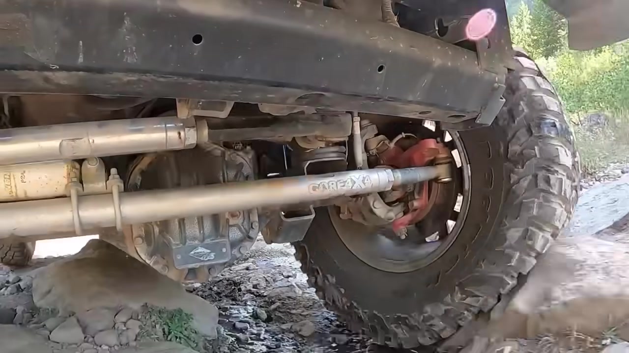 Undercarriage view of a Jeep on the trail showing Core 4x4 branded adjustable control arms at full articulation