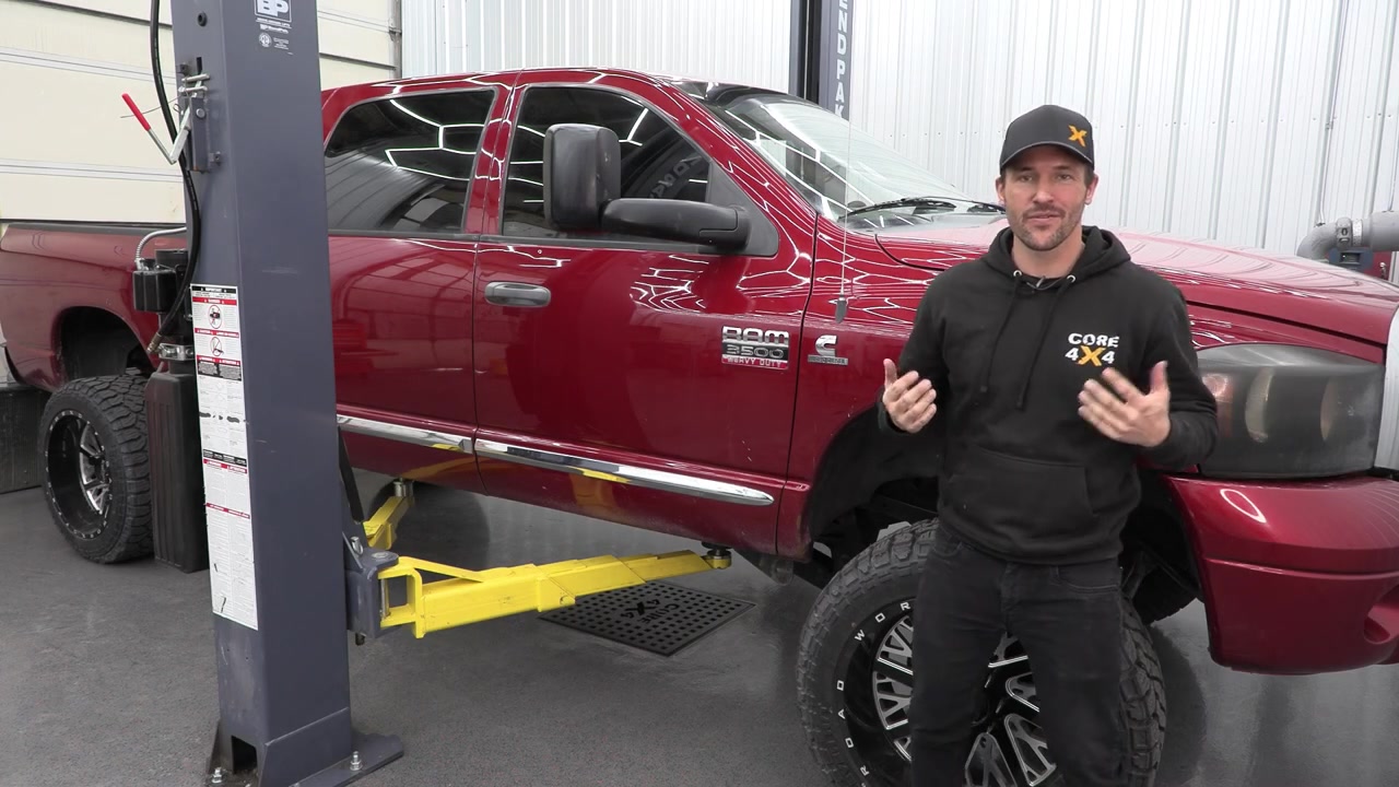Spence standing next to the Ram 3500 on the shop lift at Core 4x4, ready for the trailing arm install