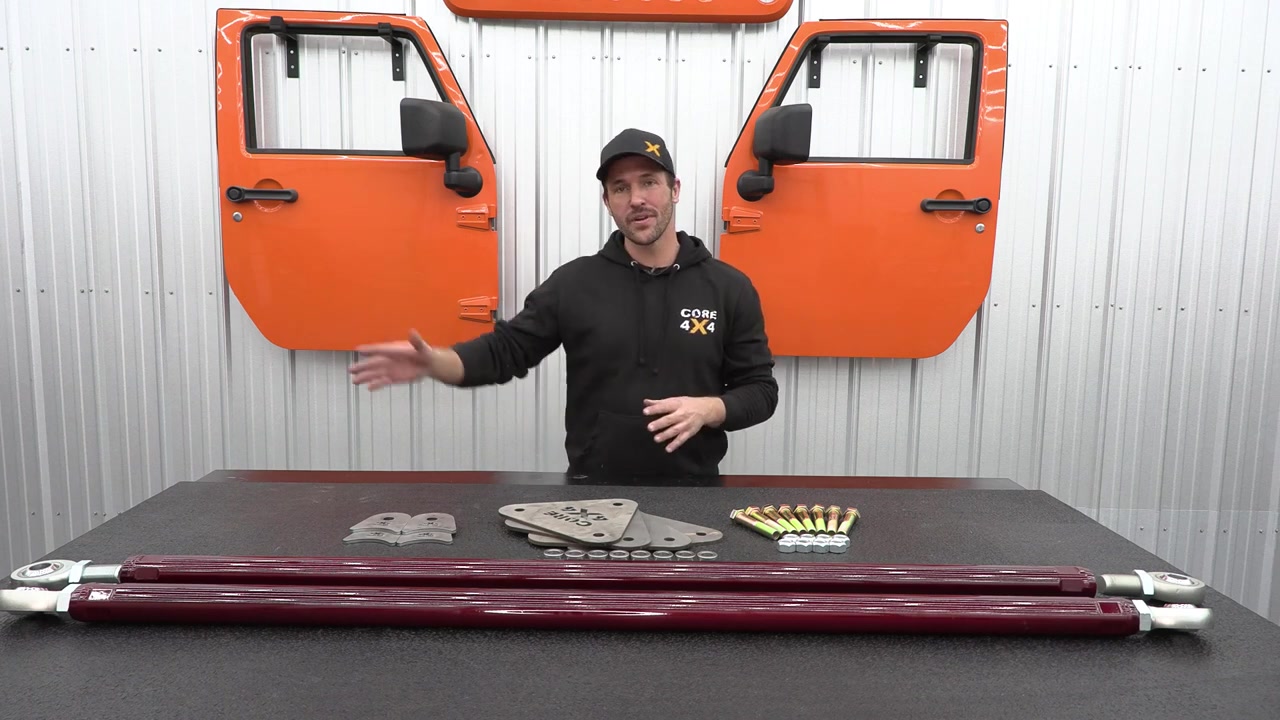 Spence at the Core 4x4 shop table with the universal trailing arm kit components: 7075 aluminum arms, quarter-plate axle and frame brackets, FK rod ends, misalignment spacers, and hardware