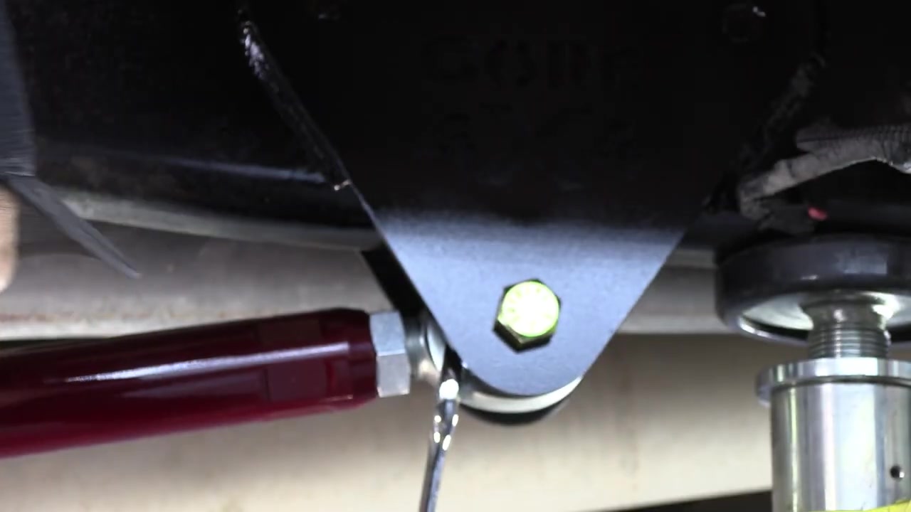 Close-up of the installed Core 4x4 trailing arm bracket and rod end connection on the Ram 3500, showing the Illusion Cherry powder-coated arm and FK rod end