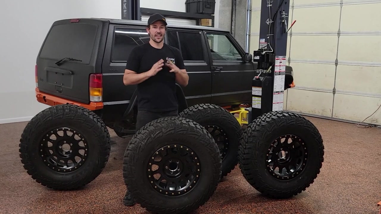 Spence presenting the five new Method wheels with Kanati Mud Hog tires mounted, lined up in front of the XJ Cherokee