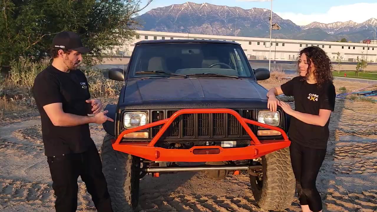 Front view of the completed XJ Cherokee with orange Dirt Bound bumper, Method wheels, and mountain backdrop