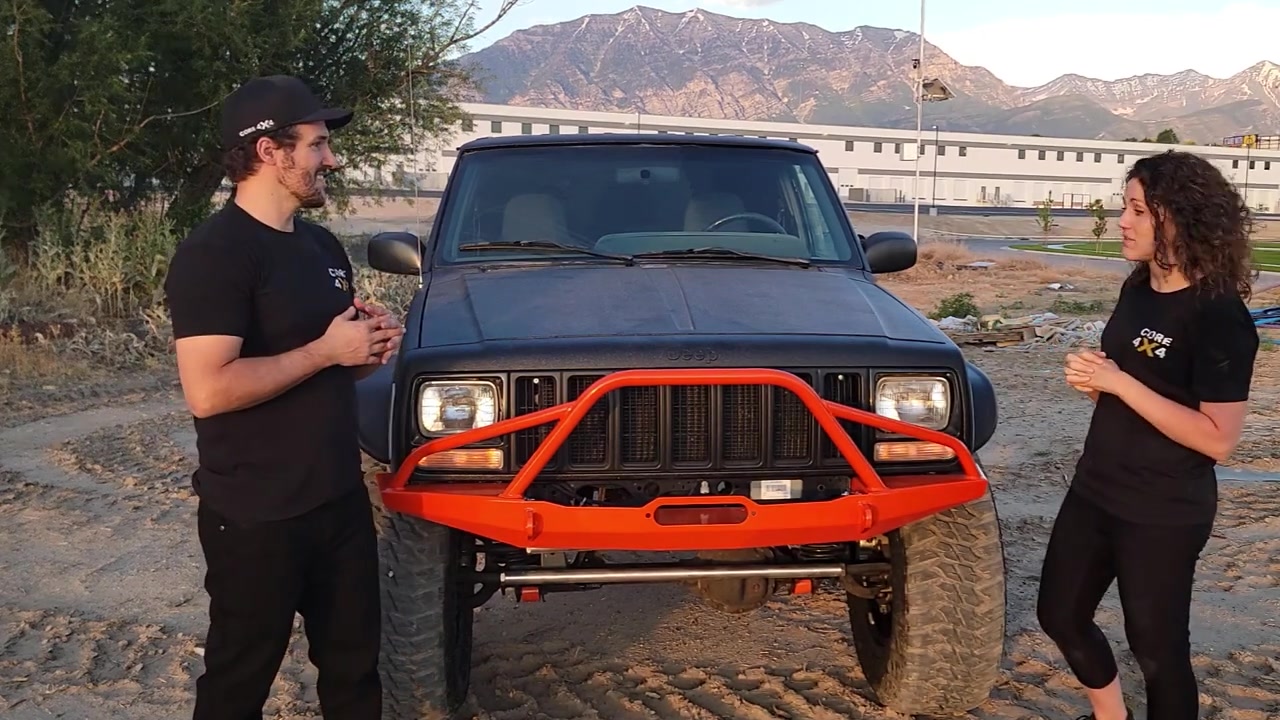 Spence and Marissa talking in front of the completed XJ Cherokee at the dirt lot, mountains behind