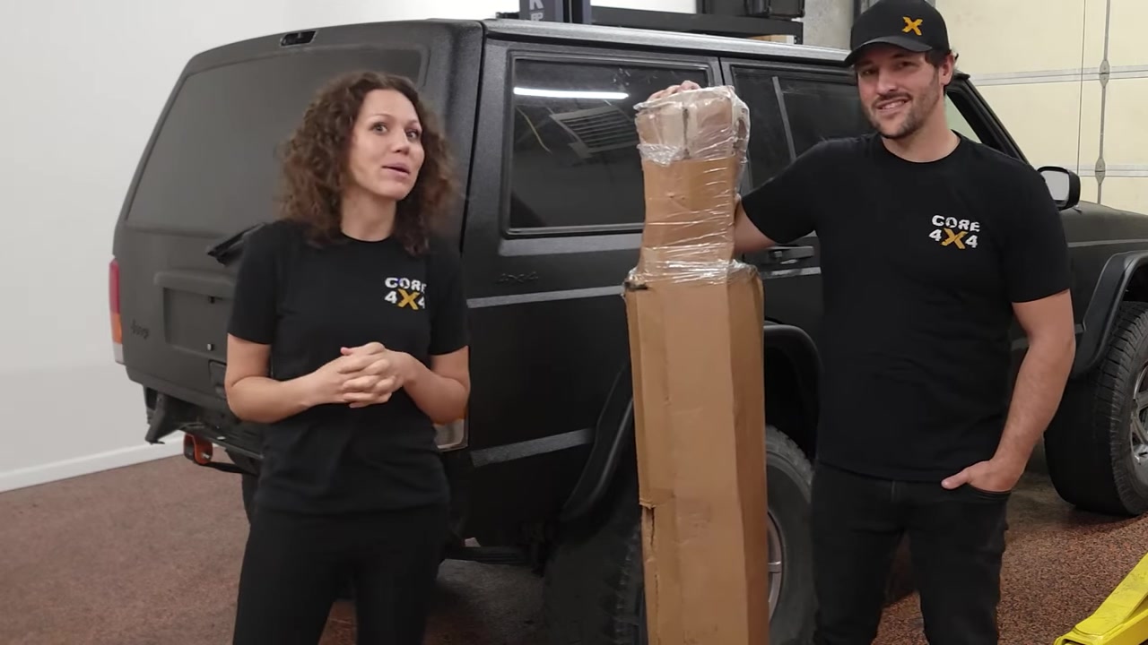 Spence and Marissa from Core 4x4 standing in front of the shop XJ Cherokee with the boxed Dirtbound rear bumper