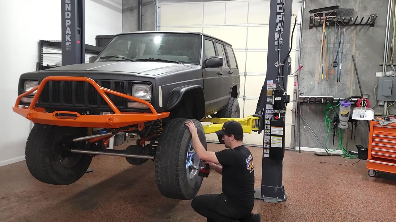 Completed XJ Cherokee with Bushwacker flat fender flares installed showing improved tire clearance with 35-inch tires and the orange Core 4x4 bumper