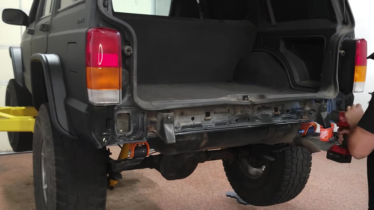 Rear of the XJ Cherokee with old bumper removed, showing the bare frame rail and old bracket mounts being taken off