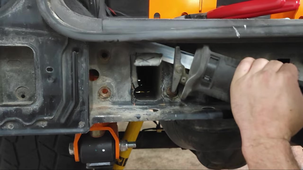 Close-up of the frame rail cutout showing the rectangular opening and bracket positioning inside the XJ Cherokee frame