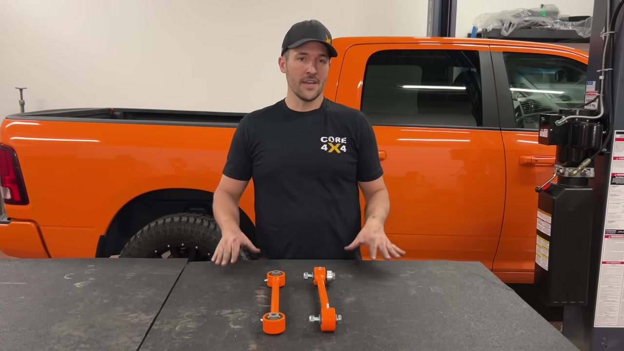 Spence explaining the Core 4x4 Track Series end links on the table with the orange Ram 1500 in the background