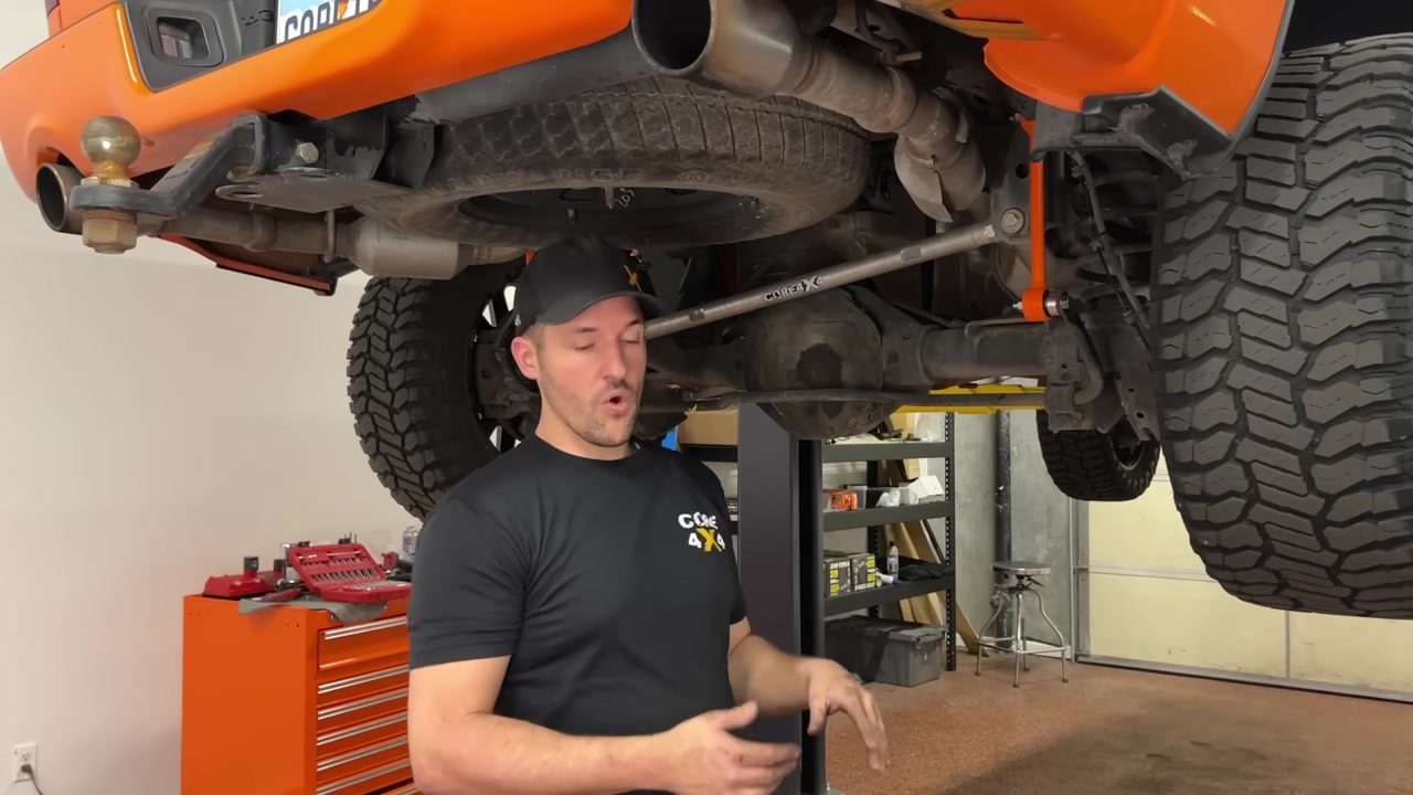 Spence standing under the completed orange Ram 1500 with both Core 4x4 Track Series sway bar end links installed on the rear axle