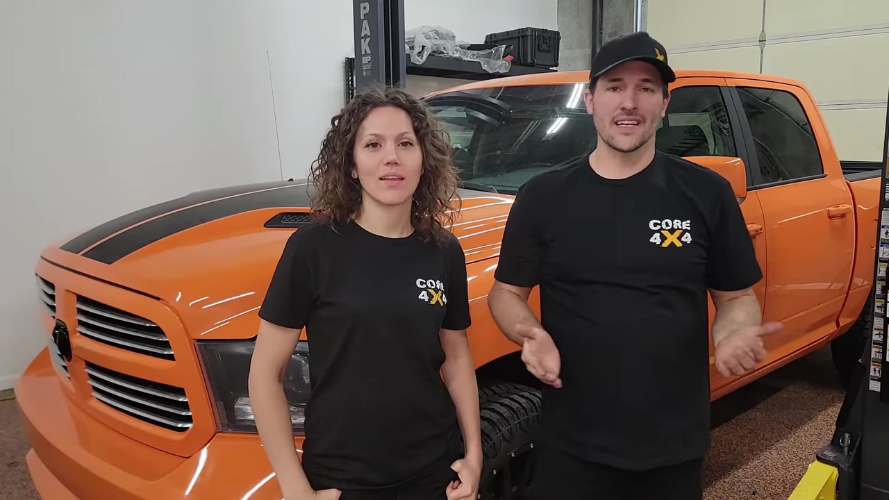 Spence and Marissa from Core 4x4 standing in front of the orange Ram 1500 shop truck in the Core 4x4 studio