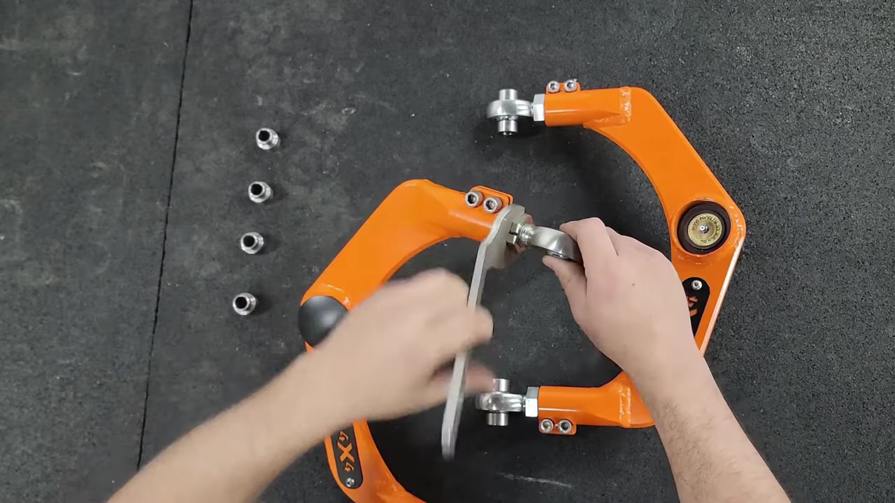 Close-up of the Core 4x4 adjustable upper control arm on the workbench showing the adjustment sleeve, clamp screws, and MOOG ball joint